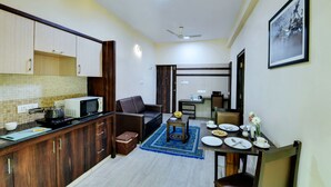 A compact kitchen with a microwave, kettle, and a small table with a blue rug. - Avm Comfort Inn (Bengaluru)