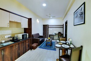 A compact kitchen with a microwave, kettle, and a small table with a blue rug. - Avm Comfort Inn (Bengaluru)