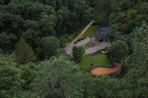 Una casa rodeada de un bosque frondoso, con un camino de entrada curvo.