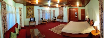 A hotel room with a large bed, a television, a desk, and a chair.