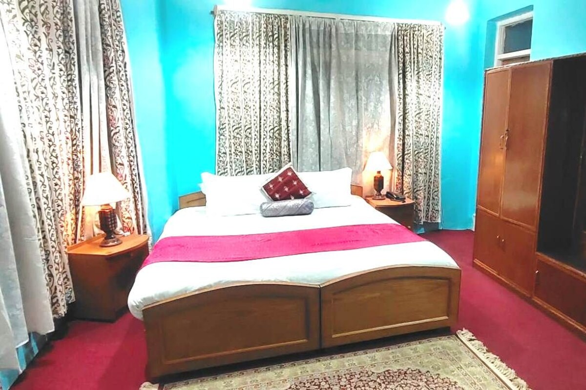 A bedroom with a bed, two bedside tables, a wardrobe, and curtains.
