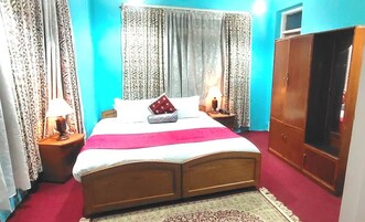 Un dormitorio con una cama, dos mesitas de noche, un armario y cortinas.