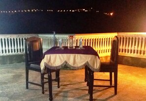 Mesa al aire libre con mantel, dos sillas y una decoración ornamental.