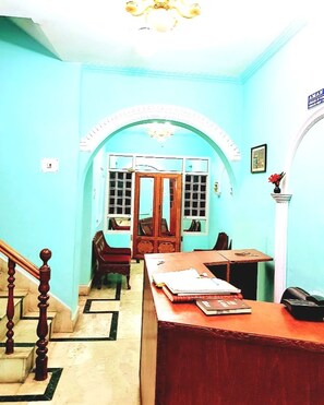 A room with a staircase, a wooden desk, a chair, and a door leading to another room. - Aman Palace (Srinagar)
