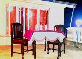 An outdoor dining area with a table covered by a white tablecloth and two chairs.