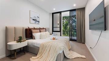 A modern bedroom with a bed, bedside table, and a TV mounted on the wall.