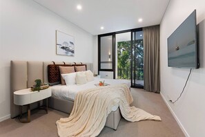 Ein modernes Schlafzimmer mit einem Bett, einem Nachttisch und einem an der Wand montierten Fernseher.