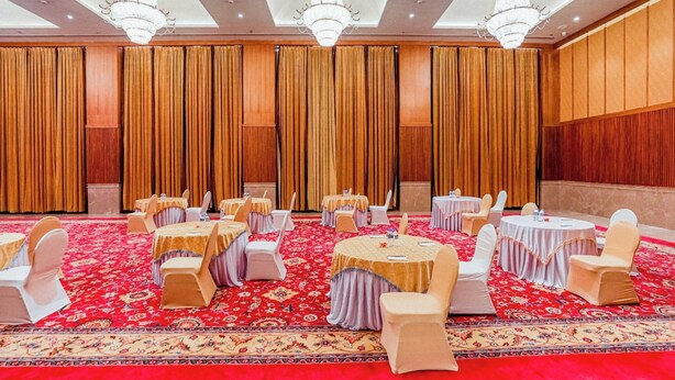 A conference room with round tables, white chairs, and a red carpet.