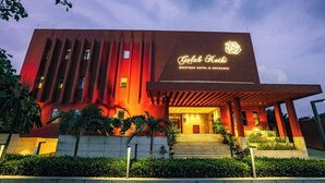 A modern building with a prominent entrance, a sign reading 'Gulab Kothi Boutique Hotel & Banquets,' and a well-lit facade.