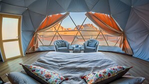 A tented accommodation with a bed, two chairs, and a view of a desert landscape. - Sun City Camp (Wadi Rum)