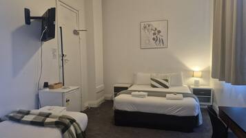 Una camera d'albergo con un letto, una scrivania, una sedia, una TV a muro e una porta.
