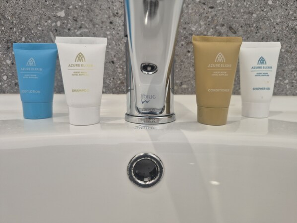 A sink with toiletries including body lotion, shampoo, conditioner, and shower gel. - The Freemasons Hotel (Bridgetown)