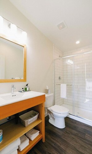 A modern bathroom with a wooden vanity, a toilet, and a glass shower enclosure. - Terra Nova Cabins (West Yellowstone)