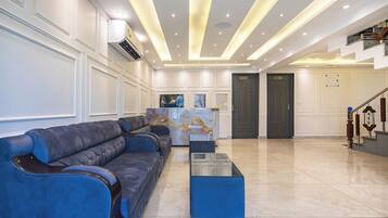 Un lobby amplio con una mesa de recepción, un conjunto de sofás azules y una escalera.