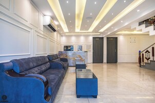 Un lobby amplio con una mesa de recepción, un conjunto de sofás azules y una escalera.