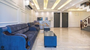 A spacious lobby with a reception desk, a blue sofa set, and a staircase. - Classy Castle (Anantnag)