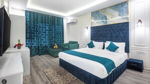 A modern hotel room with a large bed, a seating area with a small table, and a television. - Classy Castle (Anantnag)