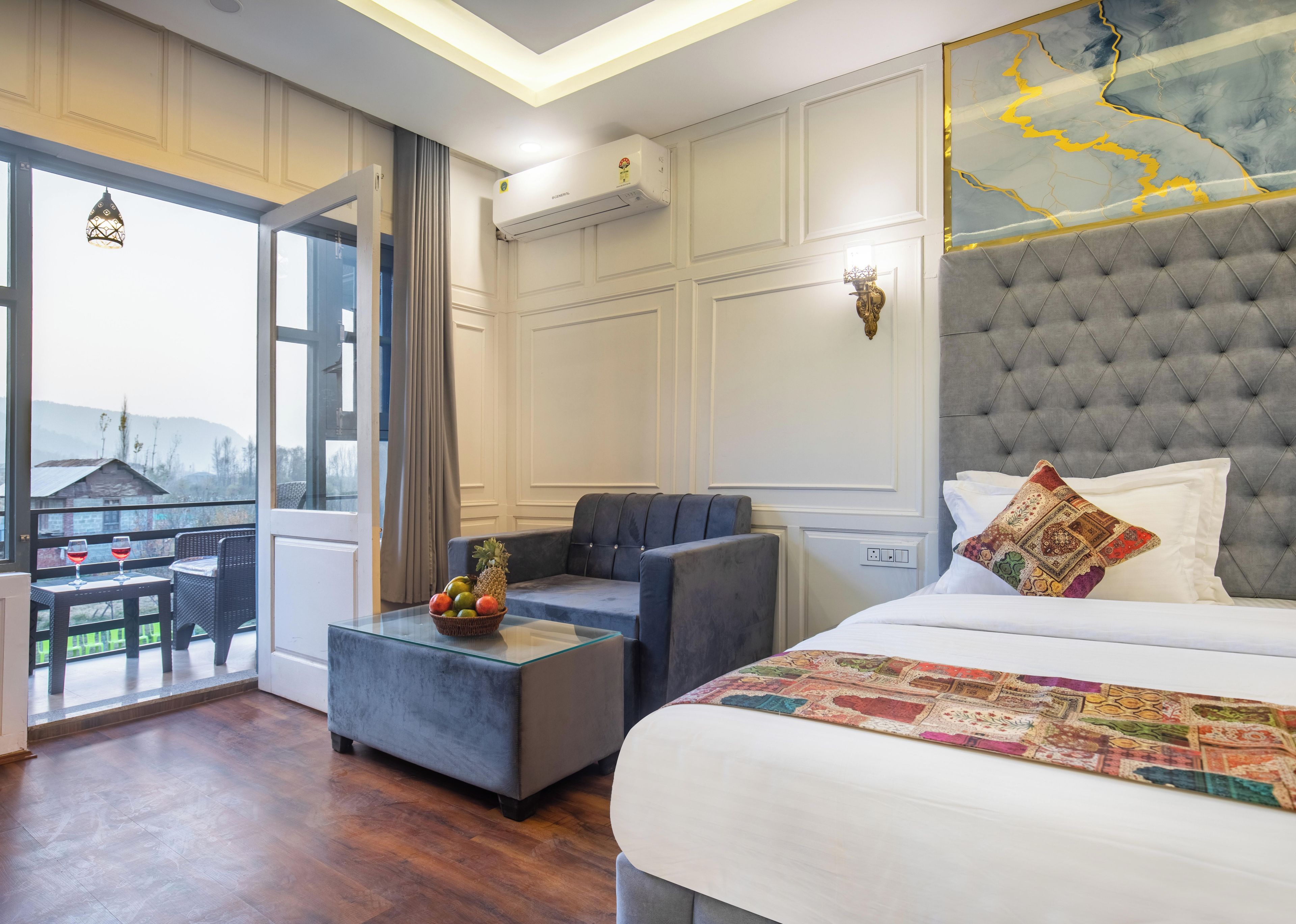 Habitación de hotel con cama, sofá, una mesita con fruta y vistas al exterior.