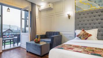 Habitación de hotel con cama, sofá, una mesita con fruta y vistas al exterior.