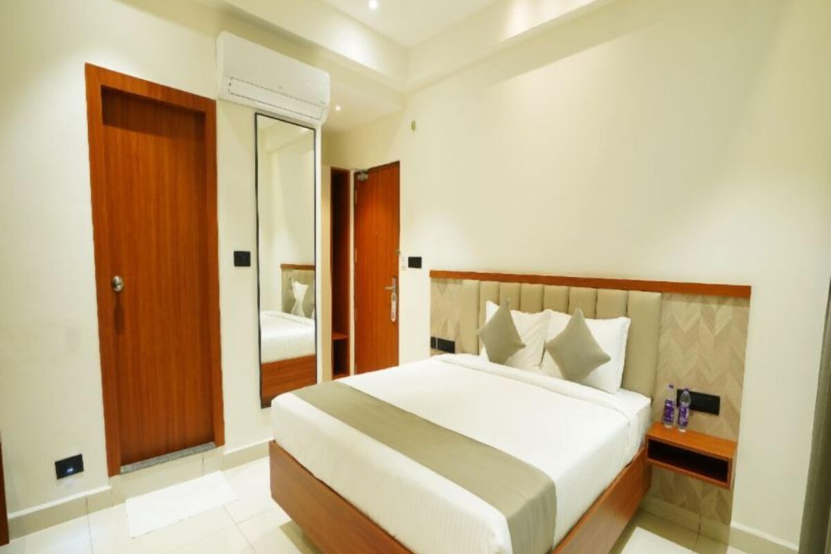 A hotel room with a large bed, a wooden headboard, a bedside table, and a mirror.