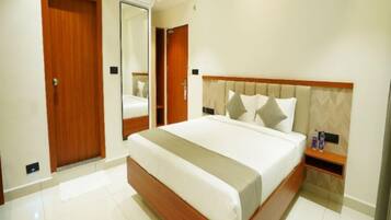 A hotel room with a large bed, a wooden headboard, a bedside table, and a mirror.