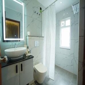 A bathroom with a sink, toilet, and shower curtain. - Leonar Hotel Kokapet (Hyderabad)