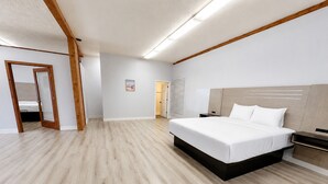 Ein modernes Schlafzimmer mit einem großen Bett, Holzbalken und einem hellen Boden.
