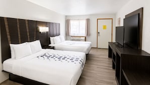 Ein Hotelzimmer mit zwei Betten, einem Fernseher und einem Fenster mit Vorhängen.