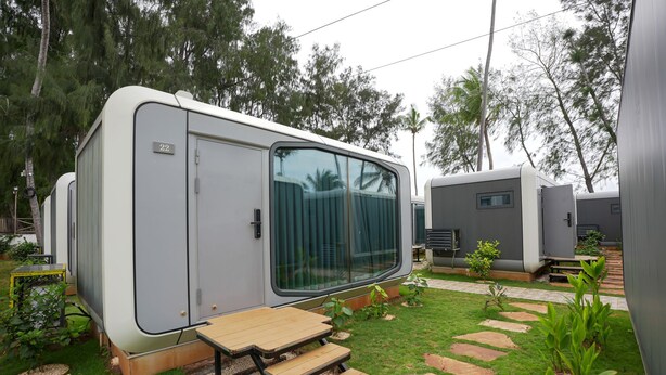 Una caravana con puerta corrediza, una pequeña zona de estar al aire libre y un sendero pavimentado.