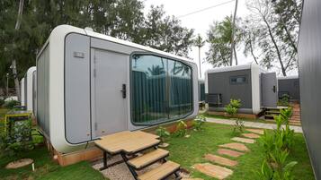 Un véhicule récréatif doté d’une porte coulissante, d’un petit espace extérieur aménagé pour s’asseoir et d’un chemin pavé.