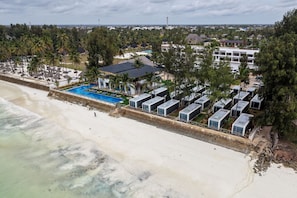 A beachfront hotel with a swimming pool, beachside cabanas, and a row of cabins. - Sea Side Beach Resort (Bwejuu)