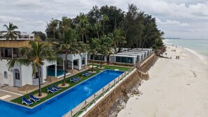 Un resort con piscina, sillas de descanso y playa.