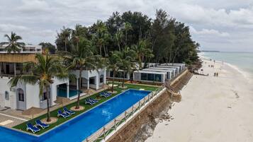 Un resort con piscina, sillas de descanso y playa.
