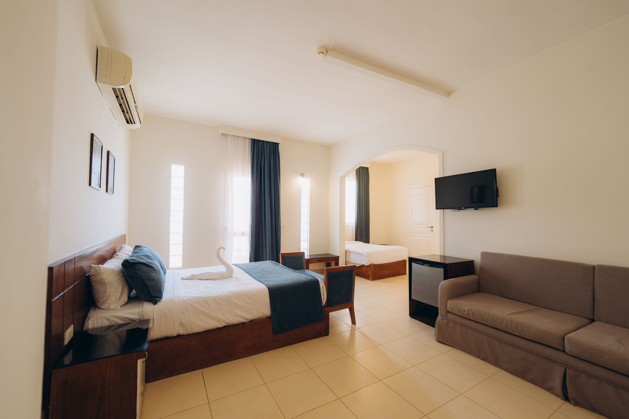 Een hotelkamer met een bed, een sofa, een televisie en een bureau.