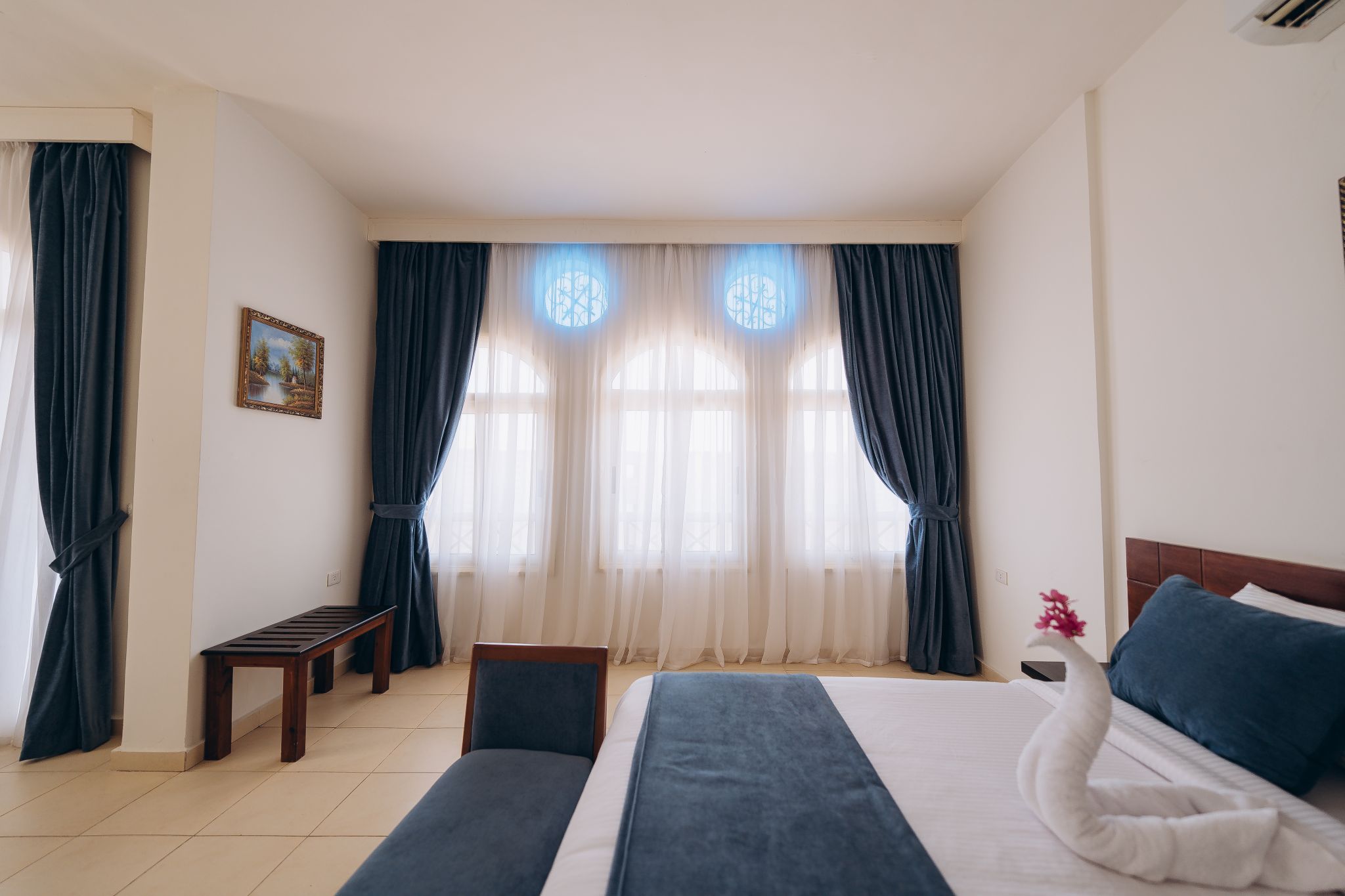 Een hotelkamer met een bed, een stoel, een tafeltje en een raam met gordijnen.