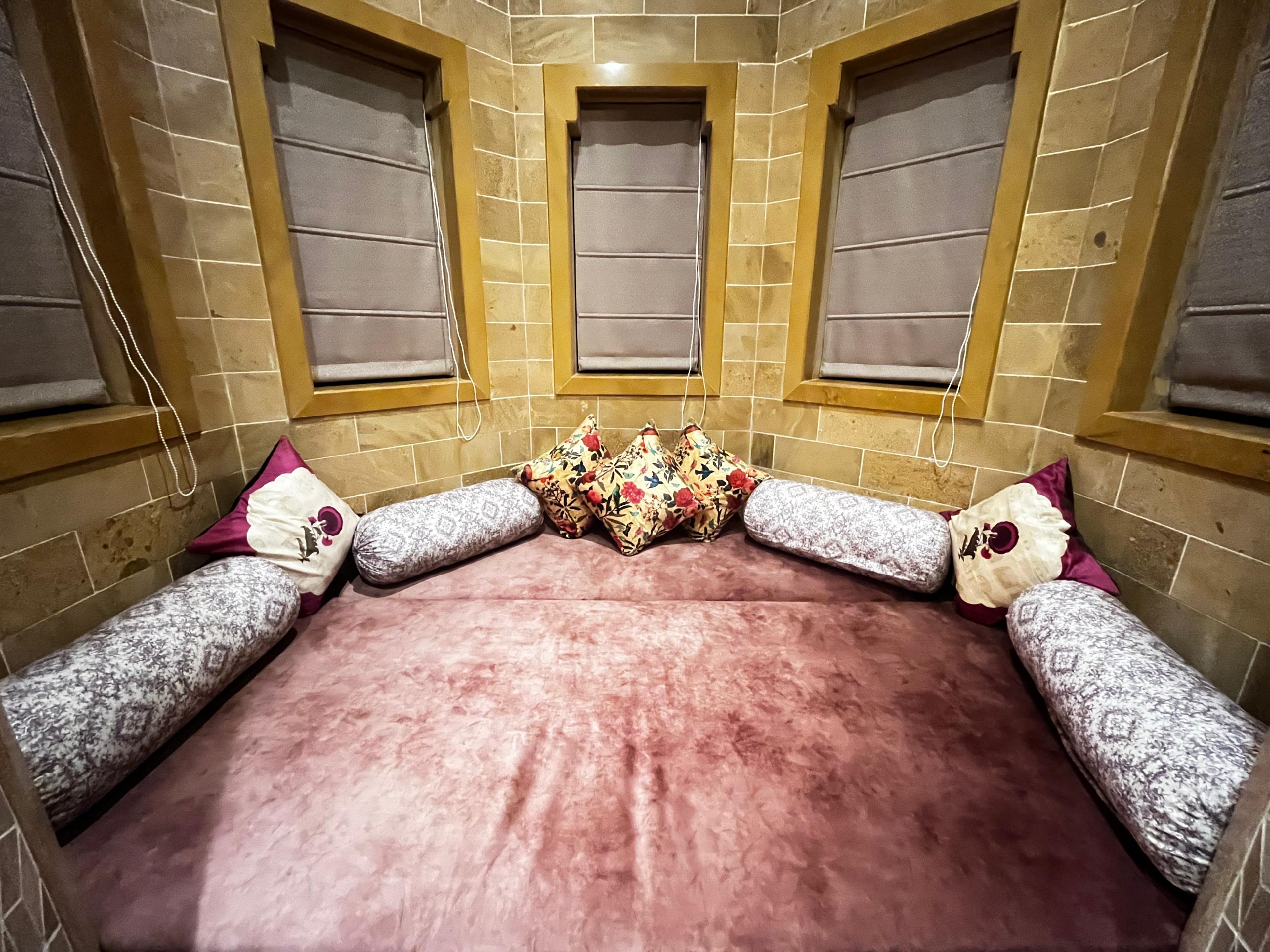 A room with a large bed, two windows, and a tiled wall.