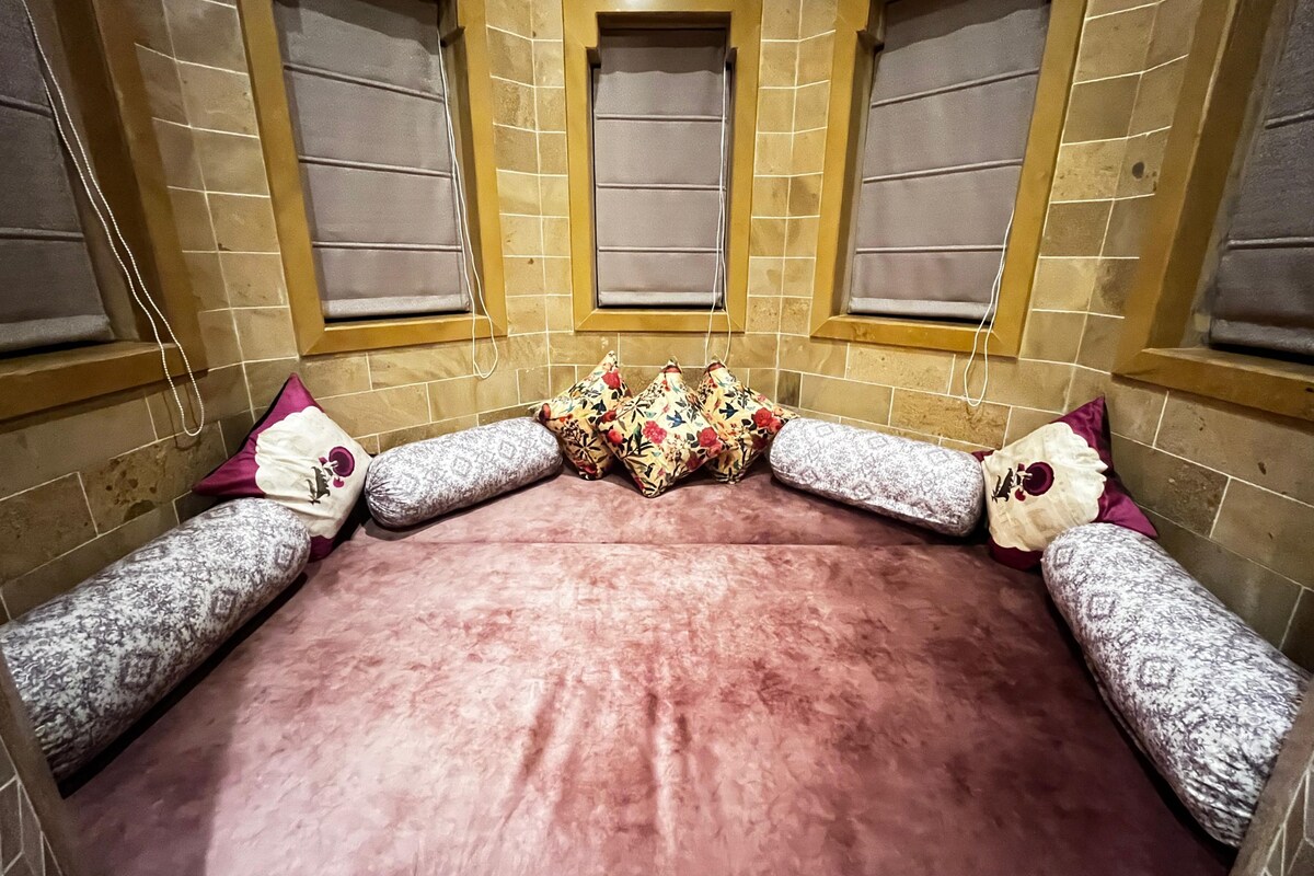 A room with a large bed, two windows, and a tiled wall.