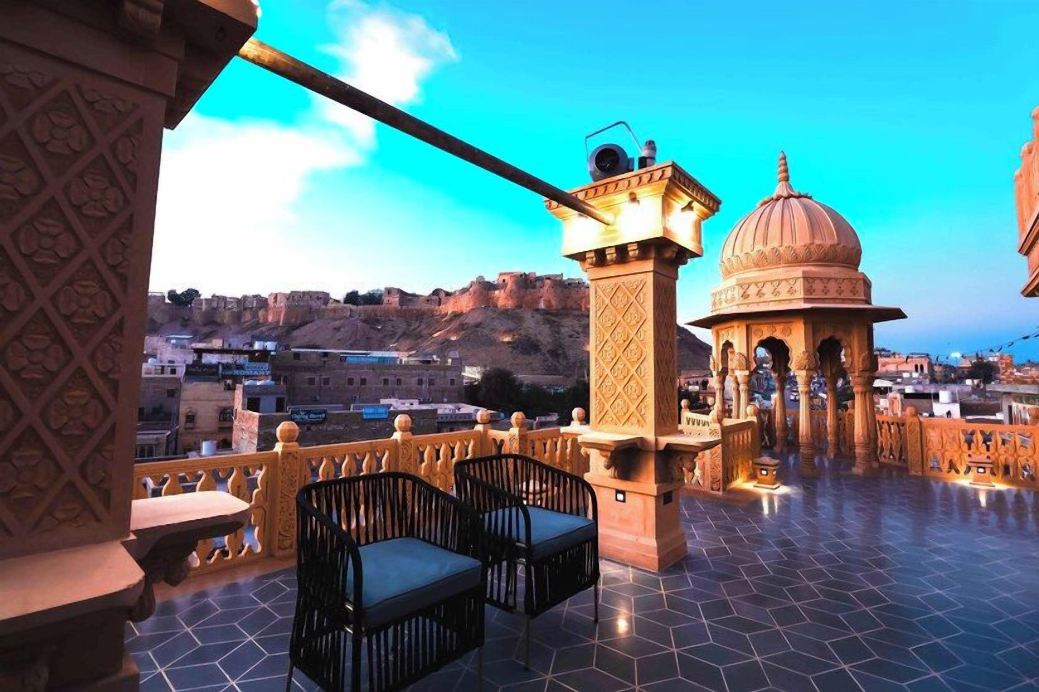 Una terraza con vistas a una fortaleza histórica, una lámpara decorativa y un pequeño pabellón.