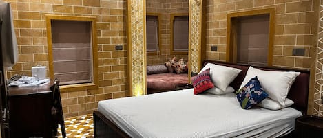 Habitación de hotel con mostrador de recepción, una cama con ropa de cama estampada, un muro decorativo y un piso con diseño.