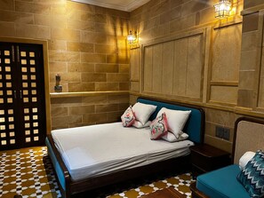Una habitación de hotel con una cama, una mesita de noche, una lámpara de pared y un piso con diseño.