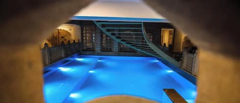 An indoor swimming pool with a view through a tunnel-like structure.
