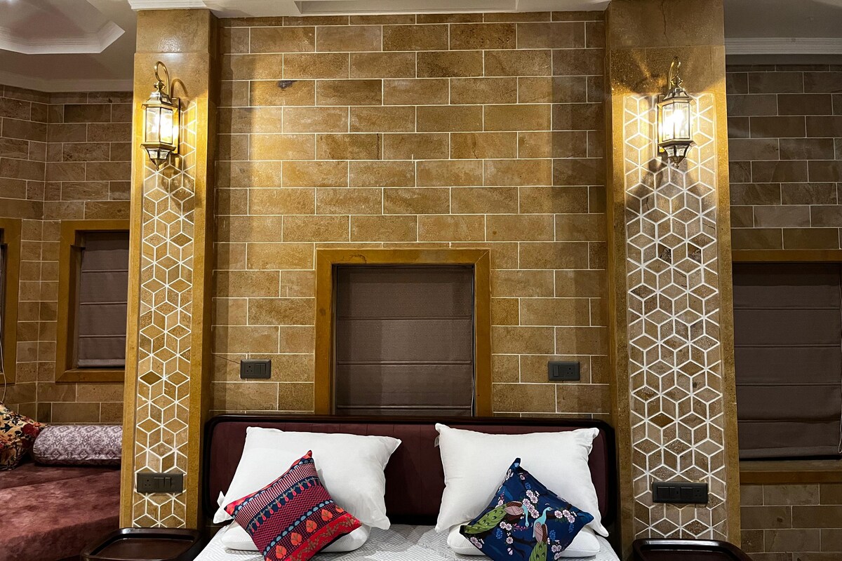 Habitación de hotel con pared de ladrillo, dos lámparas de pared, una cama con dos almohadas y una mesita de noche pequeña.