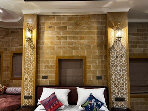 Habitación de hotel con pared de ladrillo, dos lámparas de pared, una cama con dos almohadas y una mesita de noche pequeña.