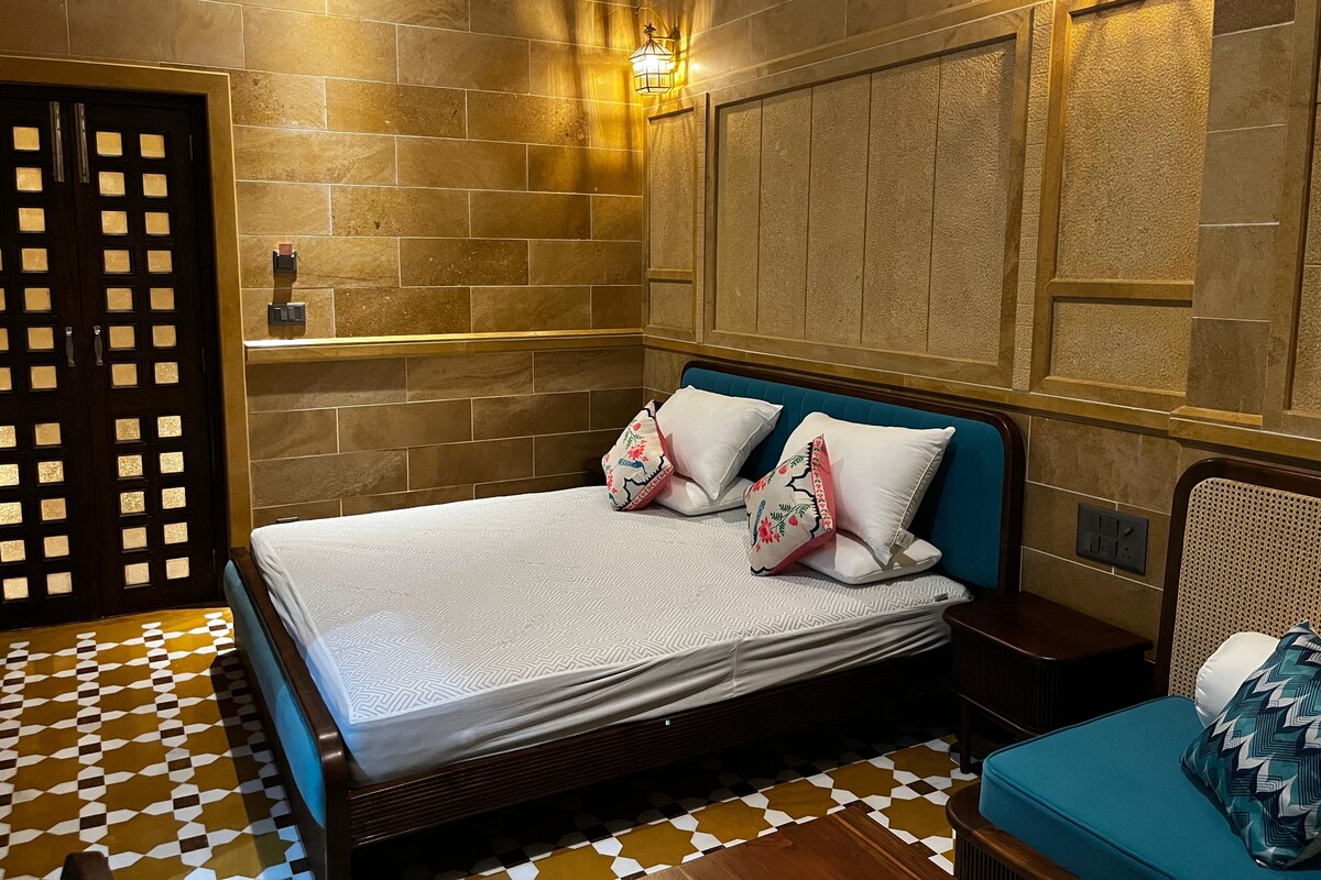 Una habitación de hotel con una cama, una mesita de noche, una lámpara de pared y un suelo estampado.
