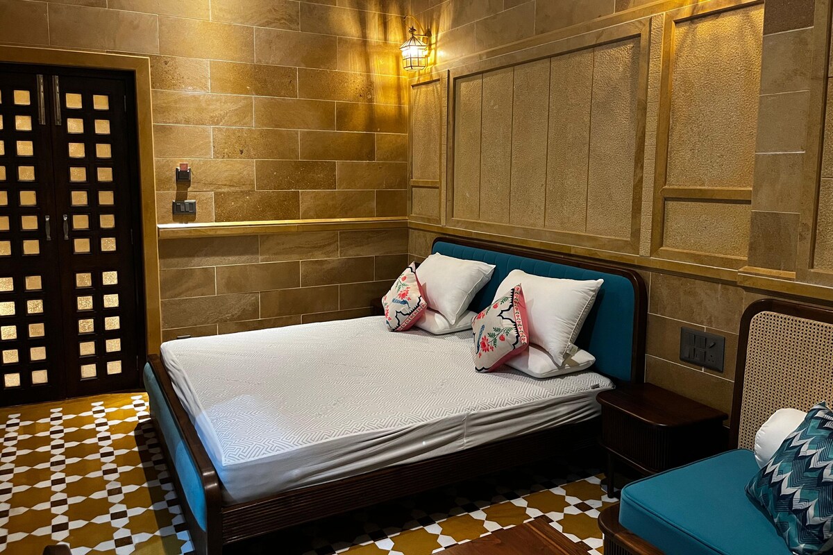 A hotel room with a bed, a nightstand, a wall-mounted lamp, and a patterned floor.