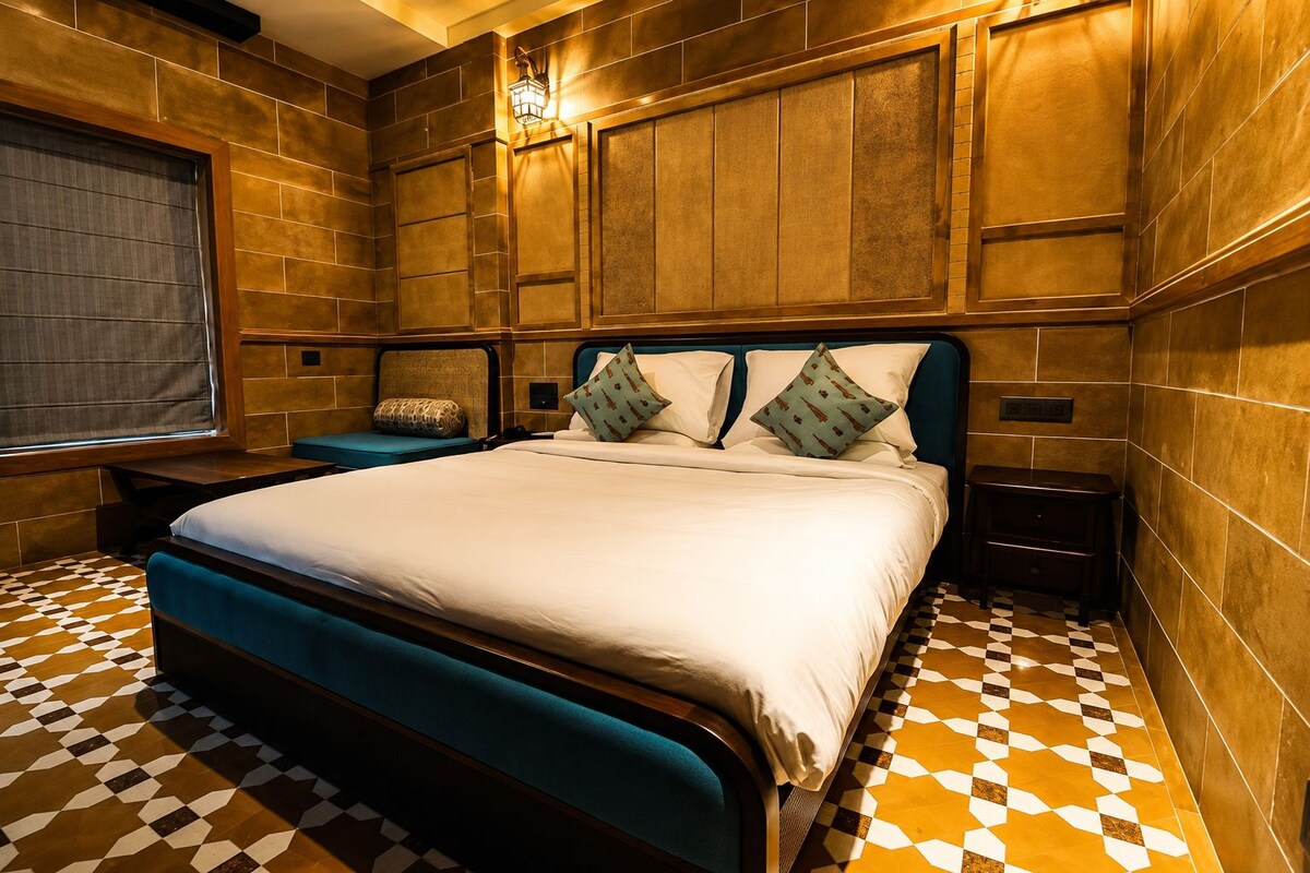 Habitación de hotel con una cama grande, una mesita de noche y una ventana con vistas.