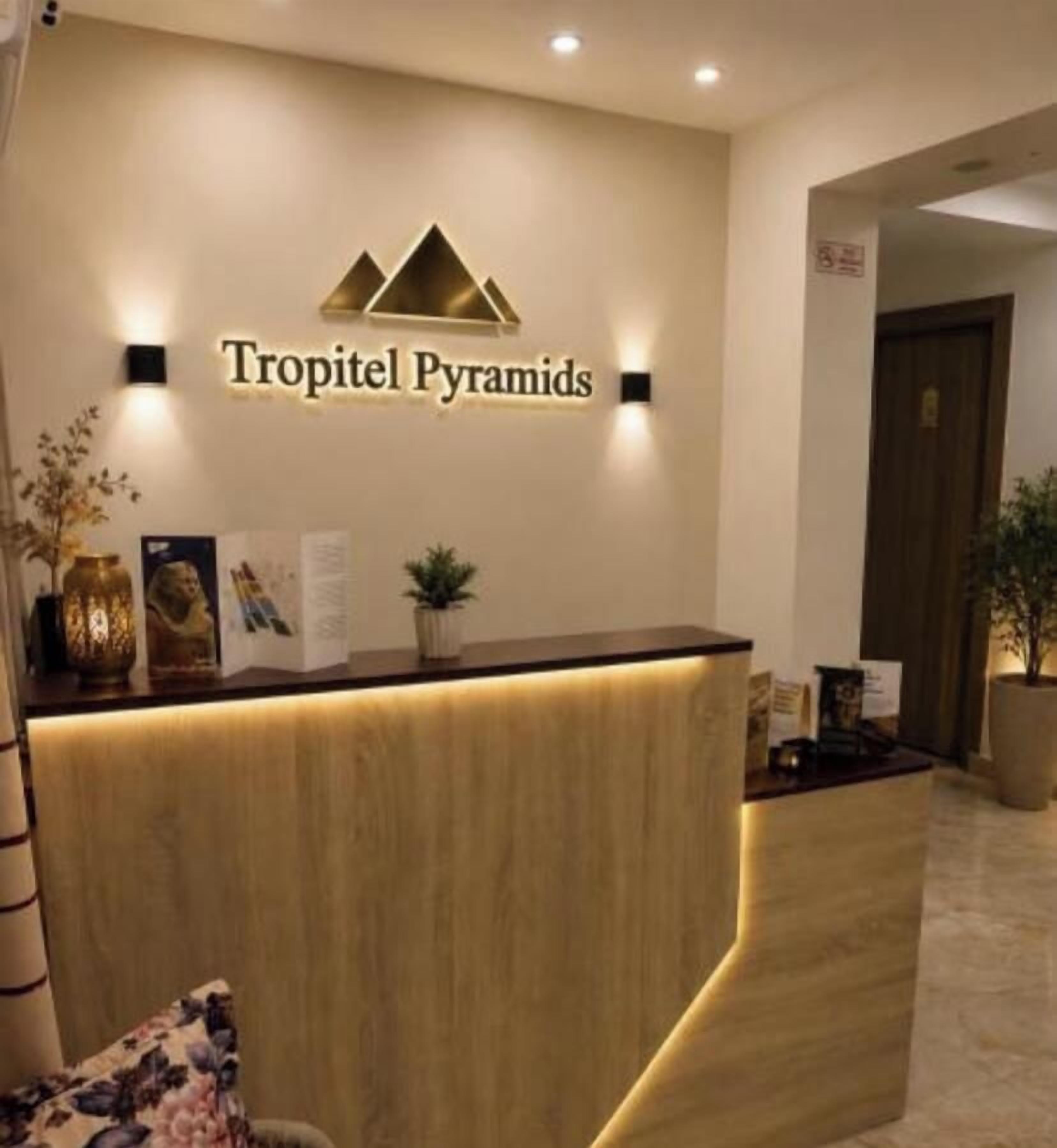 A reception desk with a logo above it, a plant on the counter, and a door in the background.
