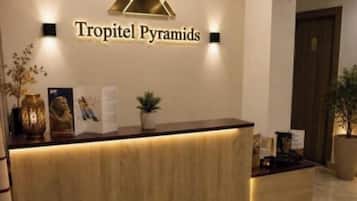 A reception desk with a logo above it, a plant on the counter, and a door in the background.