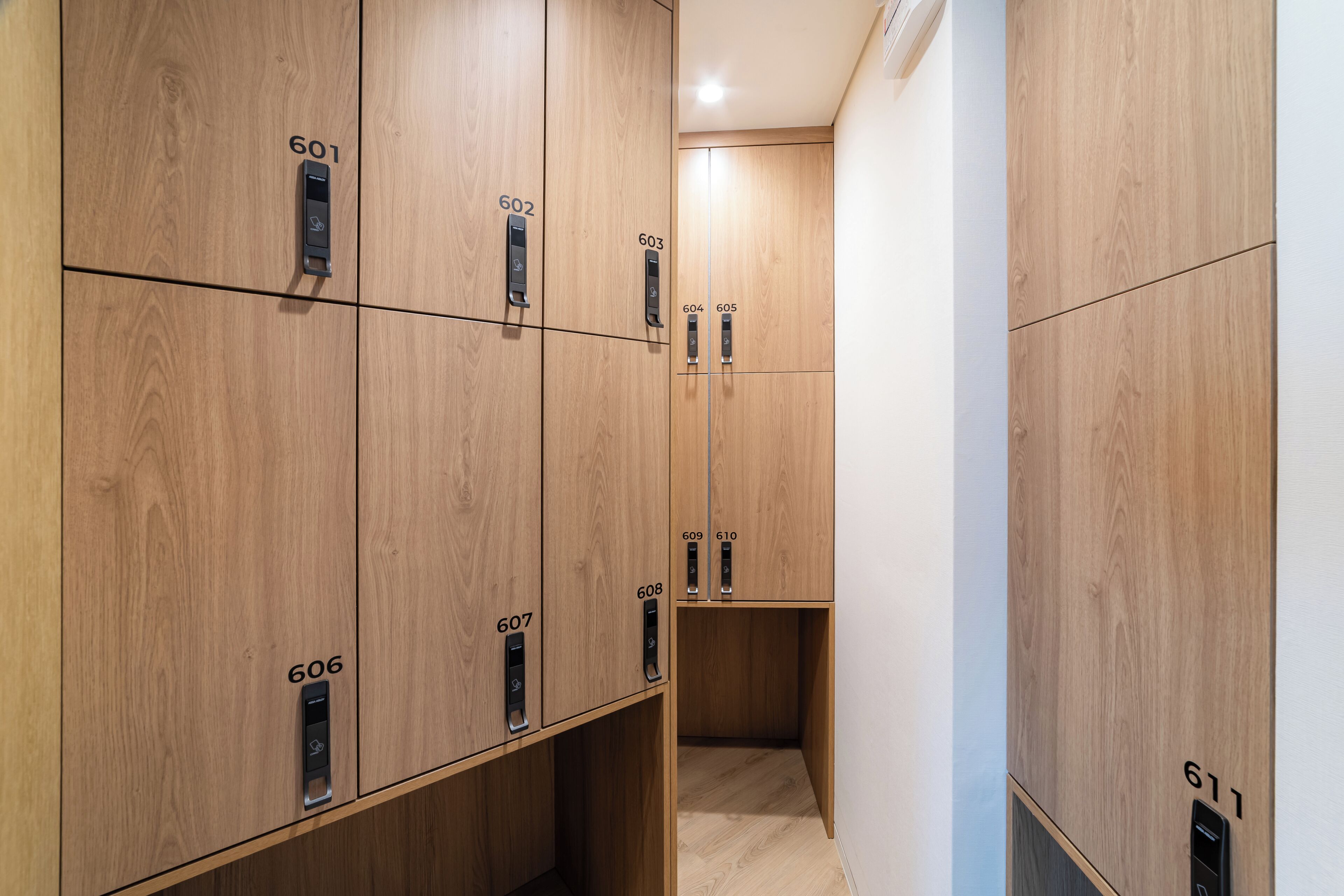A modern elevator with wooden paneling and numbered doors, leading to a hallway.