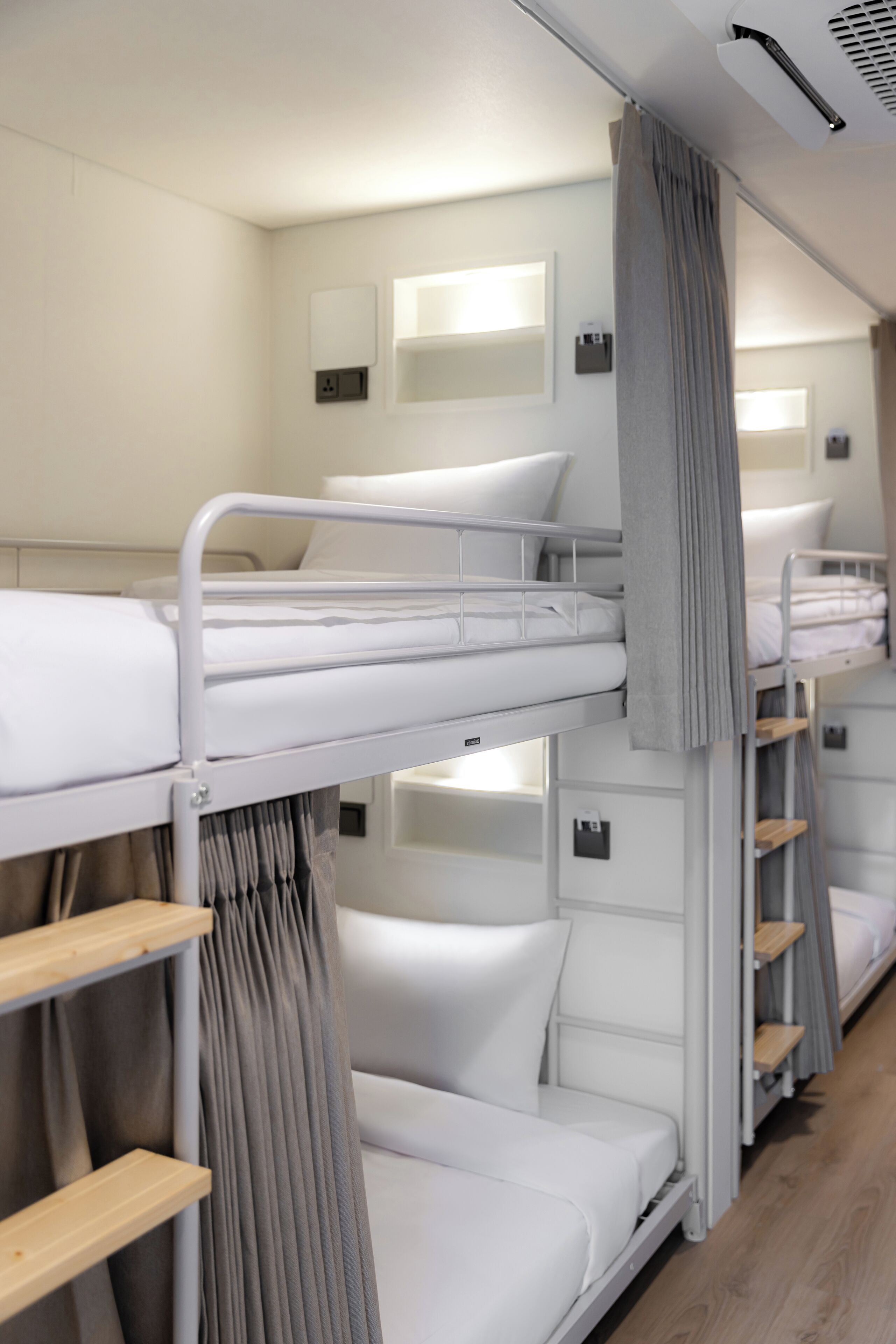 Habitación con literas, cabecera, mesita de noche y cortina.